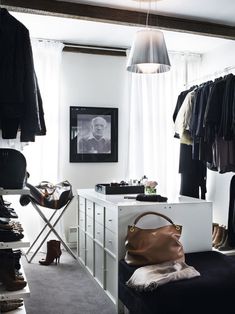 a closet with clothes, shoes and handbags hanging on the wall next to it