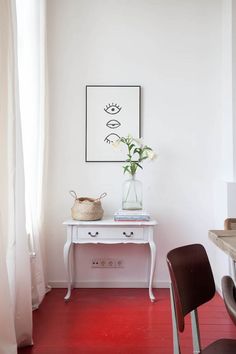 a white table with flowers in a vase on top of it next to a window