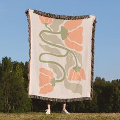 a woman standing in front of a large blanket with flowers on it and fringes around the edges