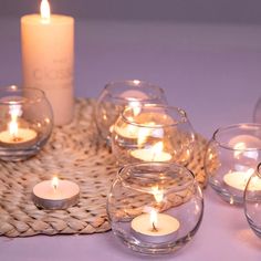 candles are lit in small glass bowls on a woven place mat and wicker tray