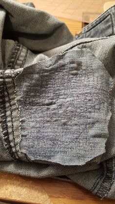 an old pair of jeans is sitting on a cutting board with a piece of wood next to it