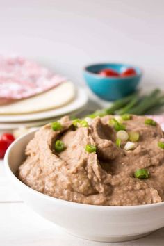 a white bowl filled with hummus and green onions