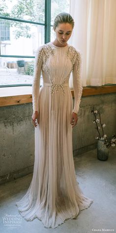 a woman standing in front of a window wearing a dress with long sleeves and beading