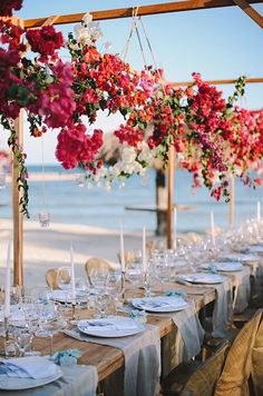 an outdoor dining area with flowers hanging from the ceiling and tables set up for dinner