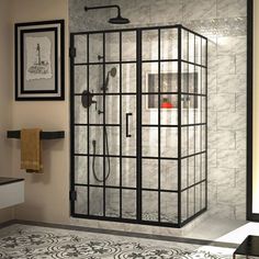 a bathroom with a walk in shower next to a white sink and black framed pictures on the wall