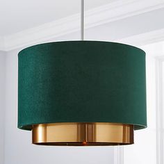 a green lampshade hanging from a ceiling in a room with white walls and windows