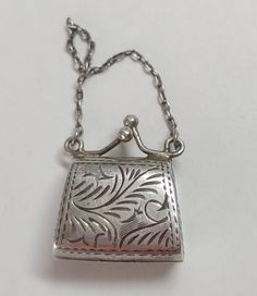 Sterling silver vintage purse charm locket. It has a hinge on the bottom so it can open up. The clasps at the top snap it tight. 4.9 grams  **This is one of our beautiful and unique vintage pieces that we purchased "over the counter" or from an estate sale.  Each piece goes through our Accredited Gemologist Association AGA certified laboratory to check the identity of the stones, metal type and quality.  It is preloved and in great condition.  We enjoy these pieces of history that give us a glimpse of the past but we are not a museum.  We price our jewelry to sell to keep our inventory moving forward and fresh.  Check back often to see new listings.  Thank you for visiting our shop.  Please contact us with any questions. Vintage Rectangular Jewelry For Everyday Use, Vintage Silver Locket Necklace With Lobster Clasp, Silver Engraved Jewelry For Everyday, Silver Engraved Jewelry, Vintage Silver Necklace For Everyday, Silver Vintage Necklace For Everyday, Vintage Hallmarked Silver Locket Necklace, Vintage Jewelry With Lobster Clasp For Everyday, Collectible Silver Metal Locket Necklace