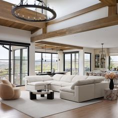 a living room filled with white furniture and lots of glass doors leading to an open floor plan