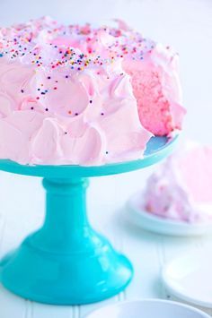 a pink cake with white frosting and sprinkles on a blue plate