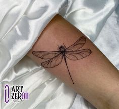 a small dragonfly tattoo on the arm