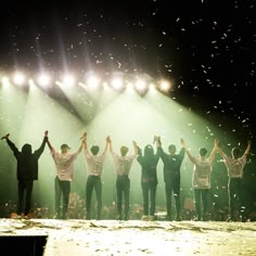 a group of people standing on top of a stage with their hands in the air