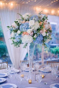 a vase filled with blue and white flowers sitting on top of a table covered in plates