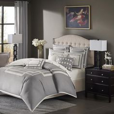 a bed in a bedroom with gray and white comforter on top of the bed