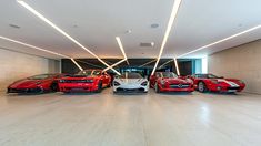 four red sports cars are parked in a large room