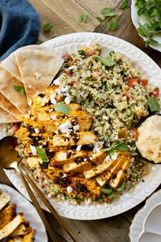 a white plate topped with chicken and rice next to tortilla shells on top of a wooden table