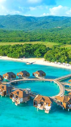 an aerial view of the water and beach with overwater cottages in the foreground