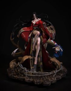 a statue of a woman sitting on top of a wooden base with snakes around her