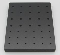 a close up of a black square object on a white surface with holes in it