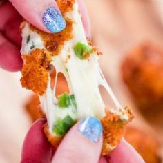 a person holding up a piece of food with white frosting and colorful candies on it