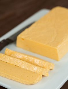 there is a block of butter on the cutting board next to two slices of cheese