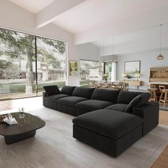 a living room with large black couches and tables in front of glass doors that look out onto the backyard