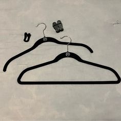 two pairs of black clothes hangers on a white surface next to an object that looks like a pair of shoes