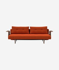 an orange couch sitting on top of a white wall