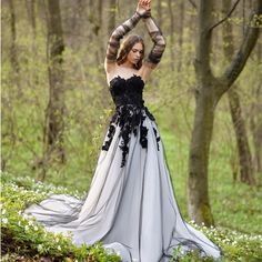 a woman is standing in the woods wearing a dress