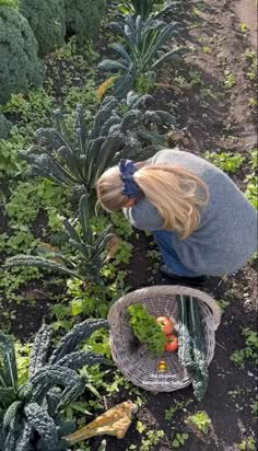 a woman kneeling down in the middle of a garden with lots of plants and vegetables