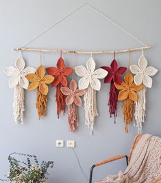 several crocheted flowers hanging on a wall next to a wicker basket and chair