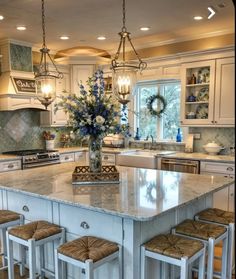 a kitchen island with four stools in front of it and flowers on the counter