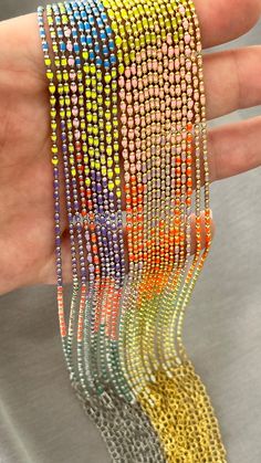 a hand holding several different colored bracelets