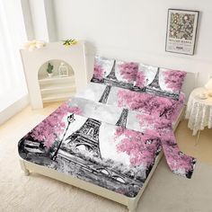 a bed with pink flowers and the eiffel tower in paris on it's cover