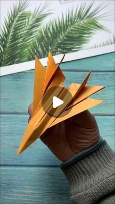 someone is holding an orange origami bird