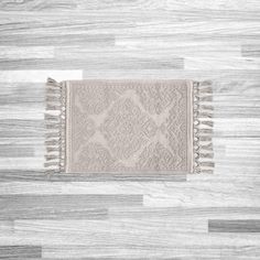 a white rug with fringes on top of a wooden floor