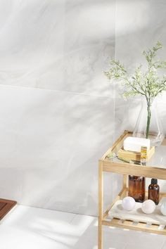 a wooden shelf with bottles and soaps on it next to a white tiled wall