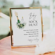 a baby sock hunt sign sitting on top of a wooden table next to a feather