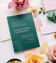 the wedding stationery is laid out with flowers