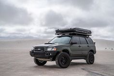 an suv with luggage on top parked in the desert