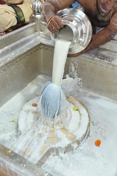 a man pouring water into a metal sink