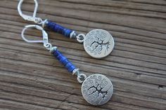 Inspired by nature, these blue dangle boho earrings are made with lapis lazuli stones, antique silver plated round charms featuring a tree of life. They hang from sterling silver lever backs. These earrings are light, comfortable and easy to wear everyday. They combine simplicity and charm to fit any casual or formal event. Color : Lapis Lazuli rondelle stones Finish : Sterling Silver lever back, Sterling Silver head pins, Antique Silver Round Tree Charms ( Lead and Nickel Free ). Length: 2-1/4 Nature-inspired Blue Dangle Earrings, Bohemian Blue Hypoallergenic Jewelry, Dark Blue Earrings, Tree Charms, Earrings Nature, Lapis Earrings, Casual Earrings, Lapis Lazuli Earrings, Earrings Gemstone