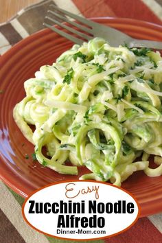 an orange plate topped with pasta and broccoli on top of a checkered table cloth