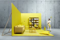 a man standing in front of a yellow room with bookshelves and furniture on the floor