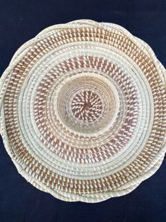 a white and brown woven basket on a black surface with an intricate design in the center