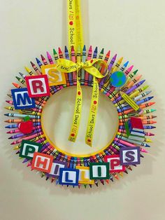 a wreath made out of colored pencils with the word smile on it and a yellow ribbon