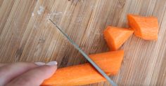 someone is cutting carrots with a knife on a wooden board and chopping them into cubes