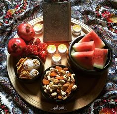 an assortment of food on a plate with candles and fruit in the middle, surrounded by other foods