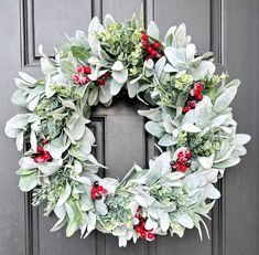 a wreath with red berries and greenery is hanging on the front door's gray door