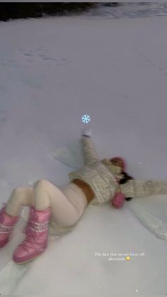 a woman laying in the snow wearing pink boots