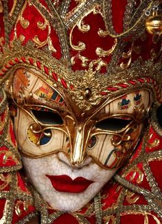 a close up of a mask with red and gold colors